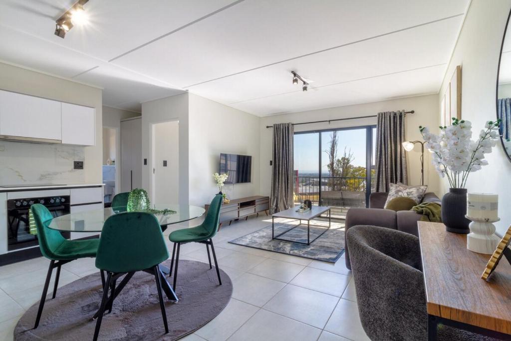 a living room with a couch and a table and chairs at AlimamaSpaces Panos Whisken in Midrand