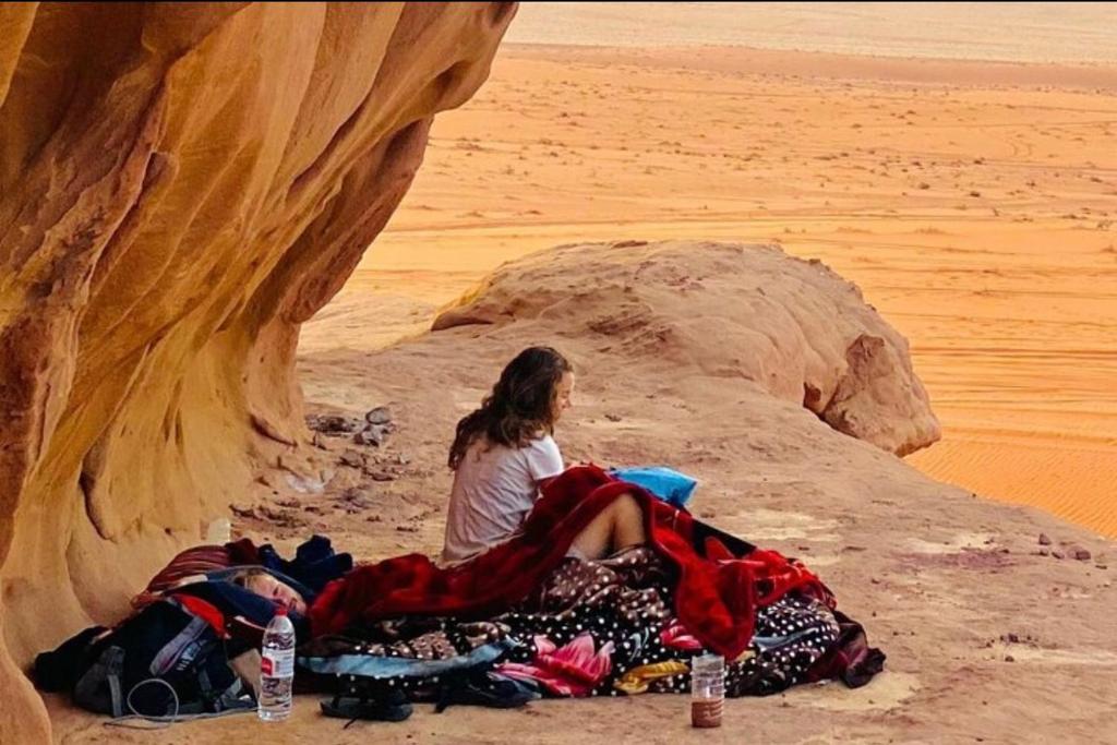 a woman sitting on a pile of clothes in the desert at Where silence connects you in Wadi Rum