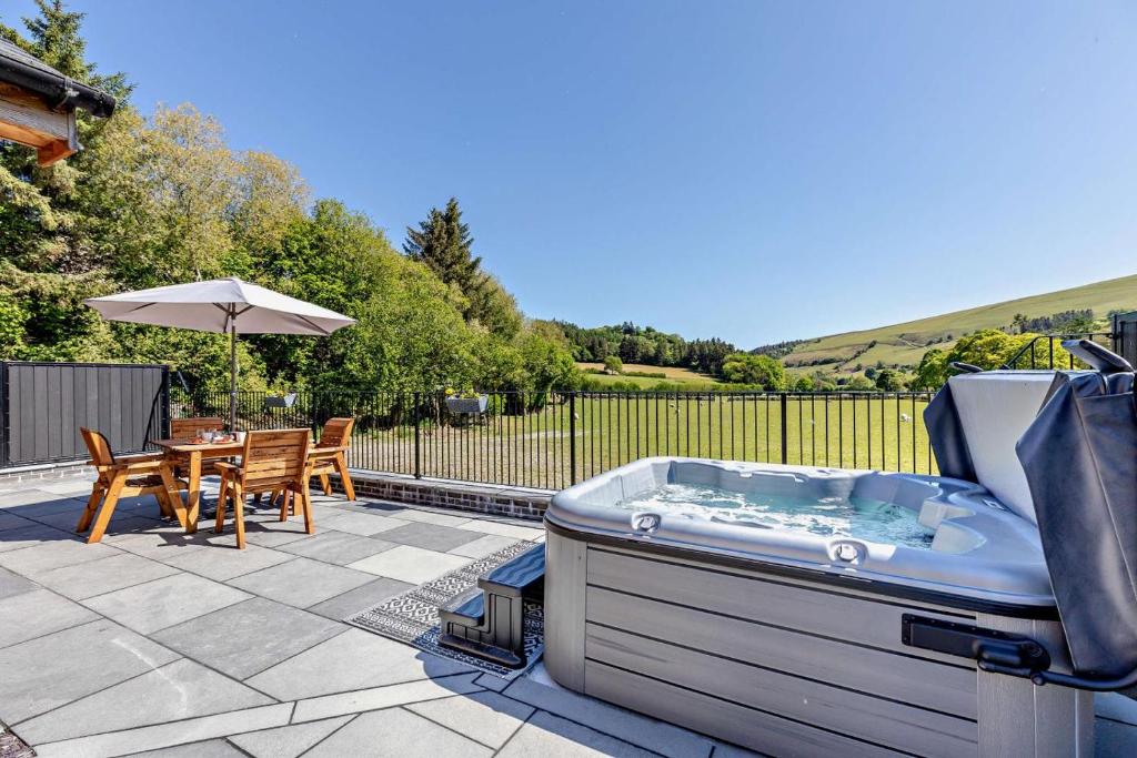 bañera de hidromasaje en un patio con mesa en Y Bwthyn Y Berwyn, en Llanarmon Dyffryn-Ceiriog