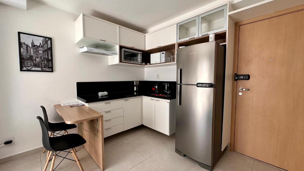 une cuisine avec un réfrigérateur en acier inoxydable et une table dans l'établissement AP822 ar condicionado piscina academia coworking etc, à Juiz de Fora