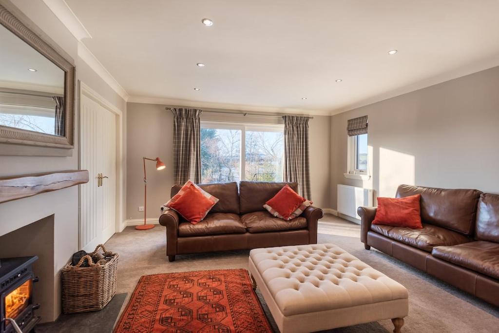 ein Wohnzimmer mit 2 Ledersofas und einem Kamin in der Unterkunft Balass Lodge near The Old Course St Andrews in Fife