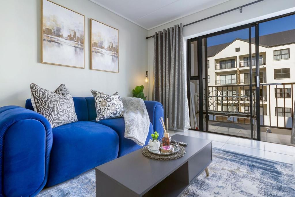 a blue couch in a living room with a large window at AlimamaSpaces Phillys Whisken in Midrand