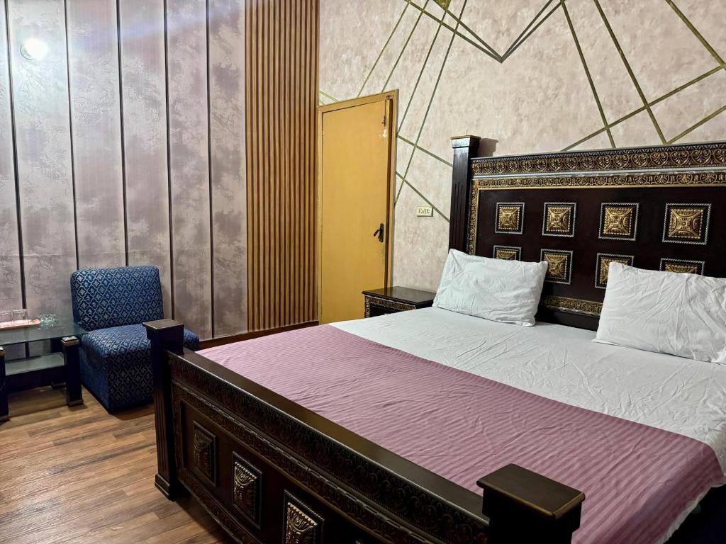 a bedroom with a large bed and a chair at Eden Plus Hotel-Garden Town in Lahore