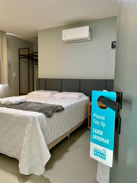 a bedroom with a bed with a sign in front of it at Campina Room Service in Campina Grande