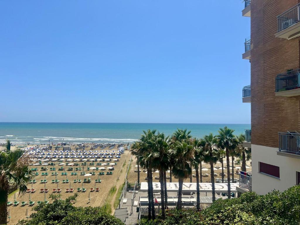 vistas a una playa con palmeras y a un edificio en Casa Vacanza Belvedere, en Nettuno