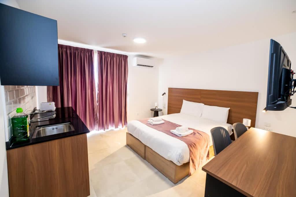 a hotel room with a bed and a flat screen tv at Bright & Cozy Studio in St Paul's Bay