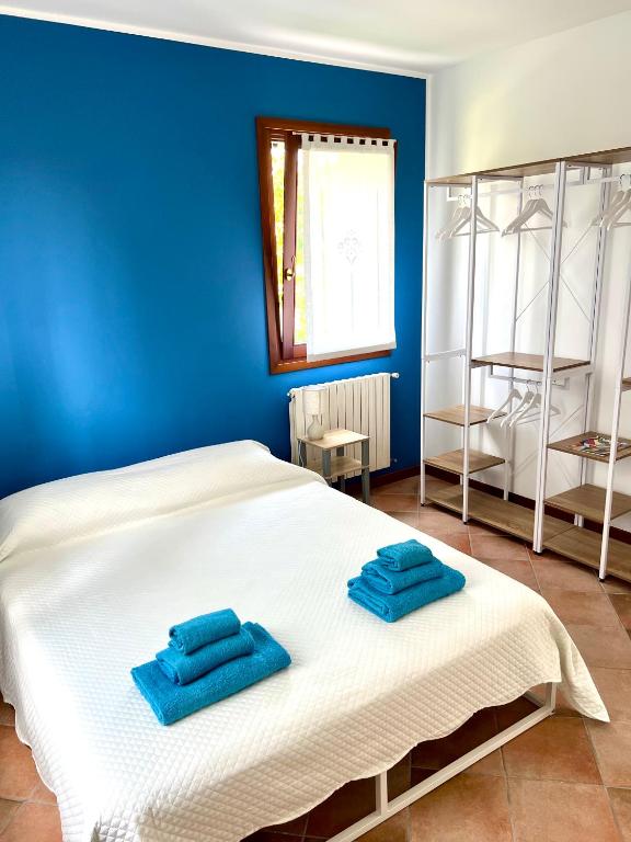 two towels on a white bed in a blue room at Villa Oasi Mariuccia - Relax e Mare in Lido di Jesolo