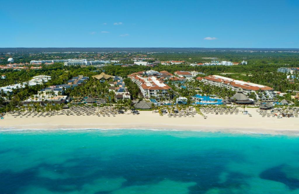 Aerial view of beachfront resort with sand, turquoise water, and palm trees.