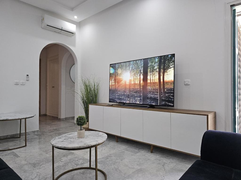 a living room with a flat screen tv on a white wall at Chic Apartment Near the Sea in Yasmine