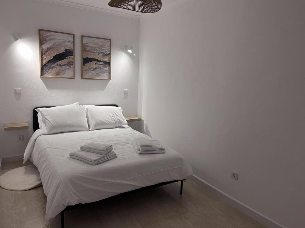 a white bedroom with a bed with towels on it at Alojamento Campo Maior in Campo Maior