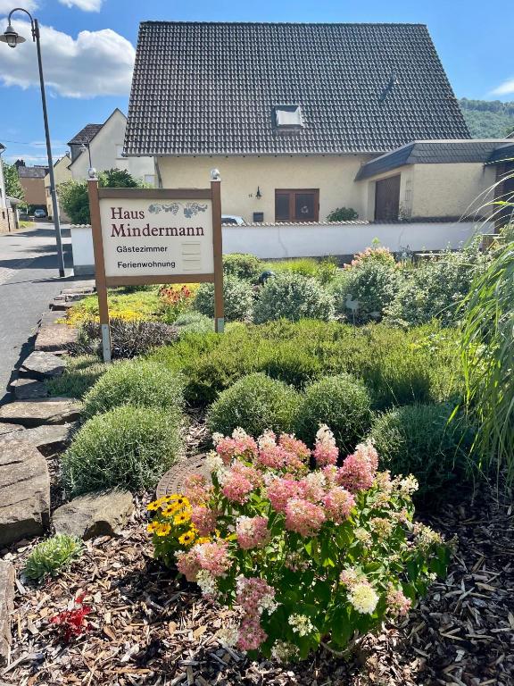 a sign in a garden with flowers in front of a building at Haus Mindermann in Bruttig-Fankel