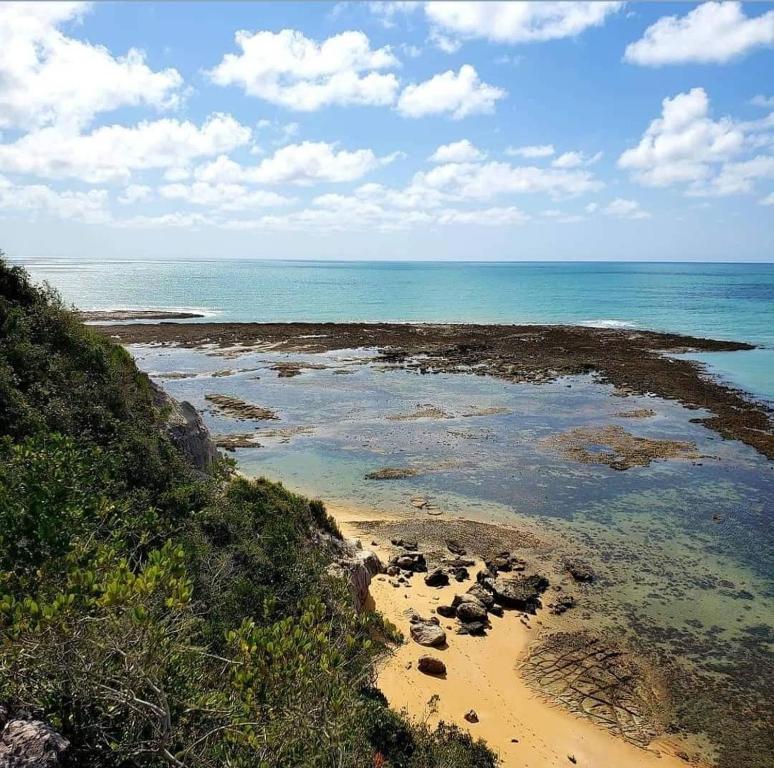 a beach with rocks and the ocean on a sunny day at Pousada Imperador do Espelho in Praia do Espelho