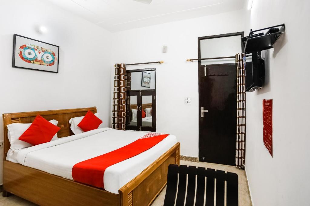 a bedroom with a bed with red pillows and a television at Hotel O Devi Palace Inn in Gurgaon