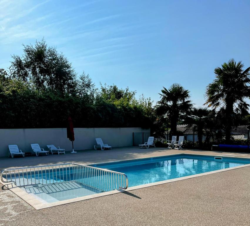 a swimming pool with two lawn chairs at Chalet familial avec piscine-Finistère Sud in Pont-lʼAbbé