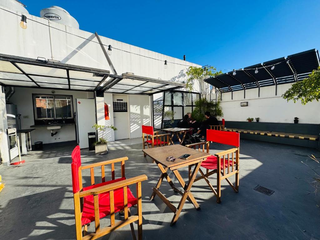 a patio with a wooden table and red chairs at Quinba Hostel in Buenos Aires