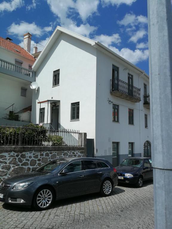 twee auto's geparkeerd voor een wit gebouw bij Casa Manuel in Manteigas