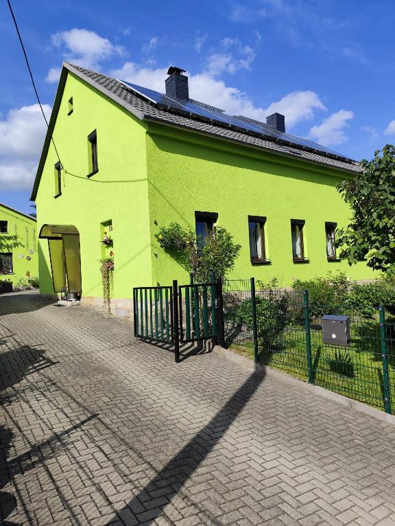 a green building with a fence in front of it at Ferienwohnung Schiekel in Sebnitz