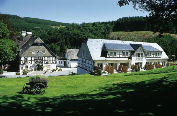 a large house on a hill with a green field at Hotel Gut Vorwald in Schmallenberg