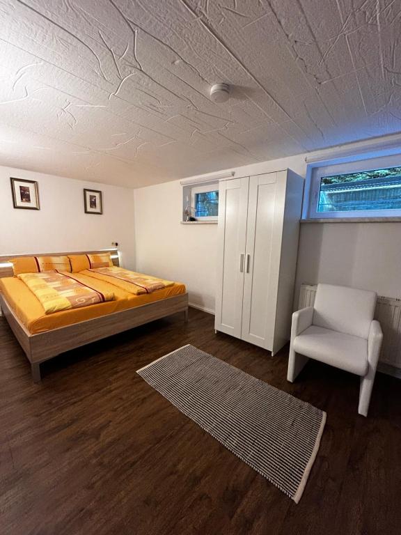 a bedroom with a bed and a chair in it at Ferienwohnung Souterrain im stielvollen Landhaus bei Hamburg in Rosengarten