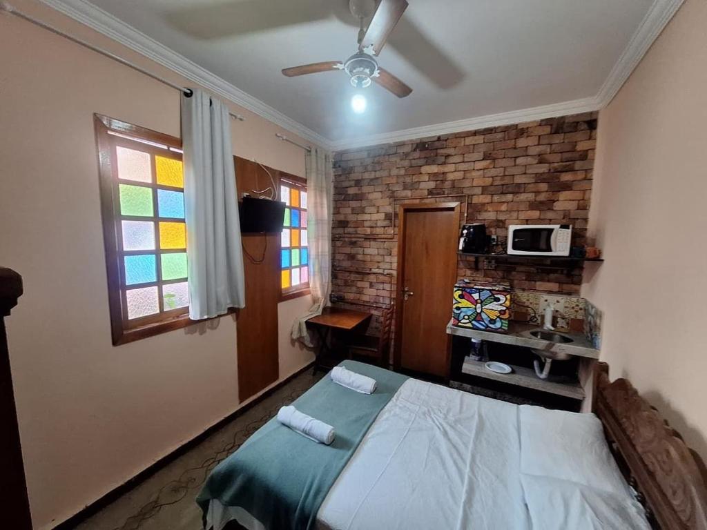 a bedroom with a bed and a brick wall at Lindo flat Sabará Estilo Europa Vila Rica Pampulha in Venda Nova