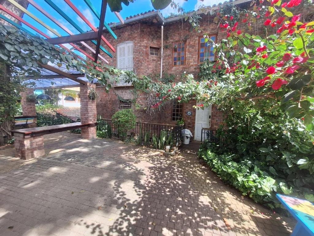a large brick house with a fence and flowers at Lindo flat Serro Estilo Europeu Vila Rica Pampulha in Venda Nova