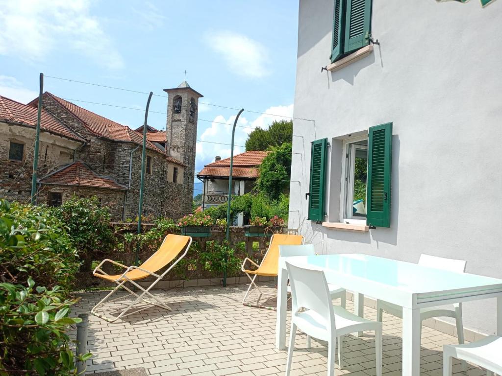 a patio with a white table and chairs and a building at Low-mountain house with terrace and garden, near Lake Maggiore in Maccagno con Pino e Veddasca