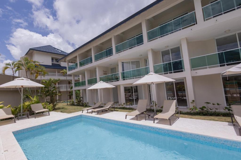 a hotel with a swimming pool with chairs and umbrellas at The beach, my happy place- One bedroom Apartment in Puerto Plata