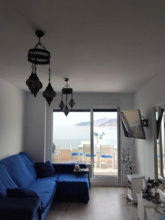 a living room with a blue couch and a large window at Sueños del Mediterraneo Estudio in Melicena