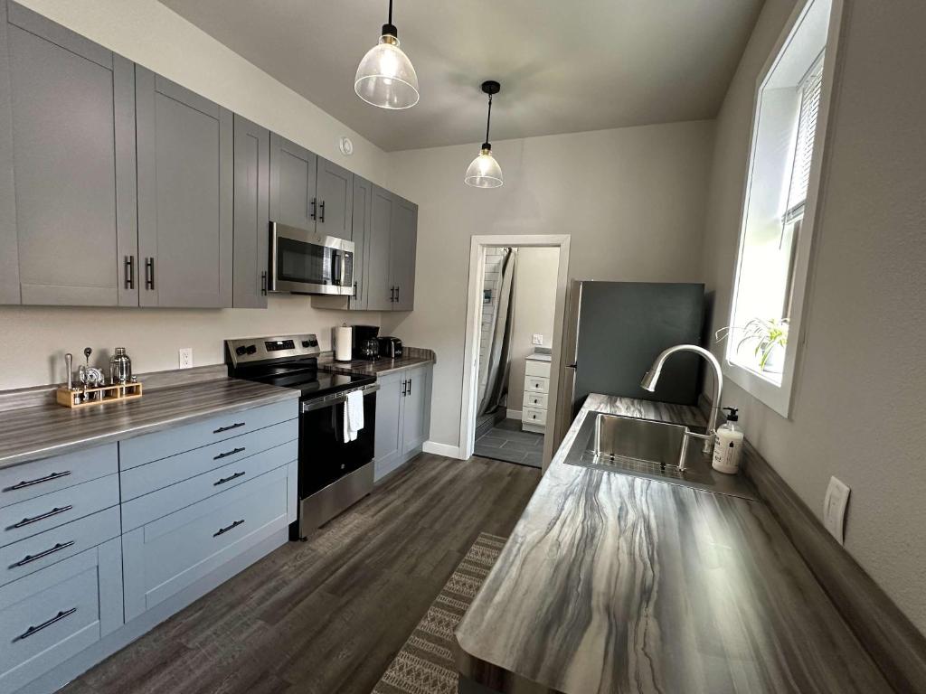 Una cocina con gabinetes blancos y electrodomésticos negros. en Downtown Minimalist Apartment, en International Falls