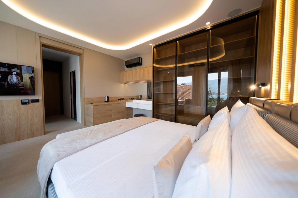 a bedroom with a large white bed and a kitchen at Boutique Hotel Lux Rooms B-Five in Budva