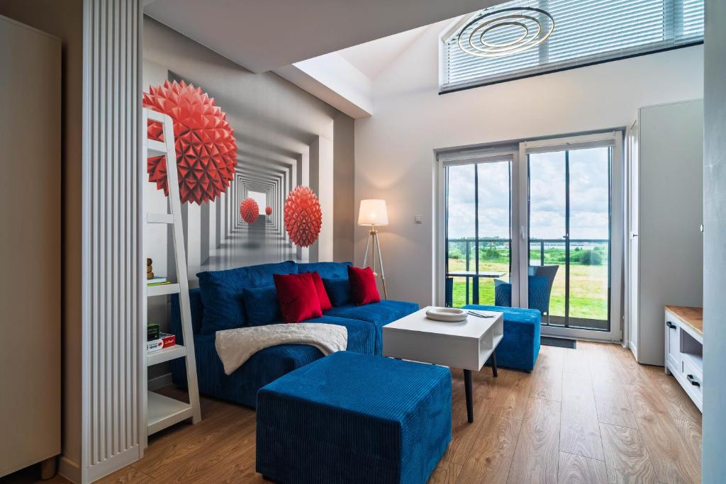 a living room with a blue couch and red pillows at Morze Apartamentów Apartament West Łeba A19 in Łeba