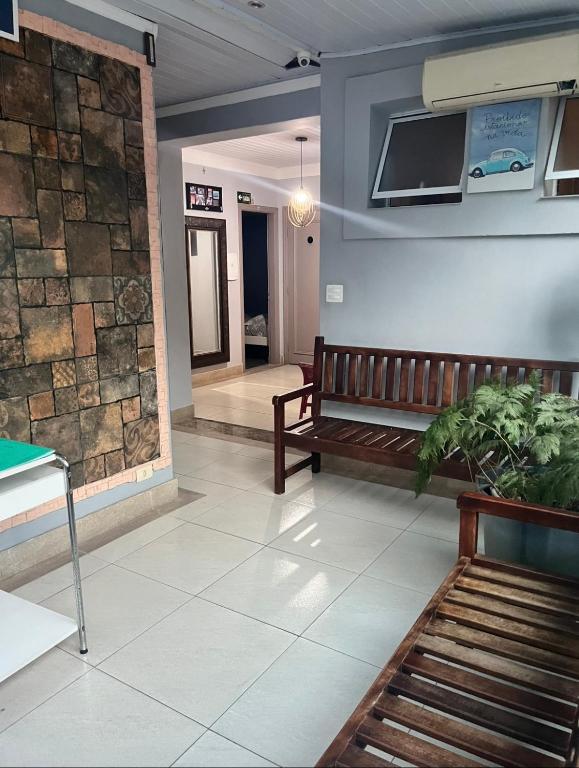 a lobby with a bench and a tv on the wall at Pousada Ohana Guarujá in Guarujá