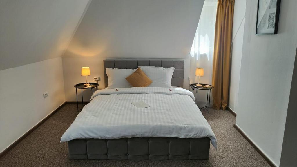 a bedroom with a large white bed with two lamps at Baroc Boutique Hotel in Topliţa