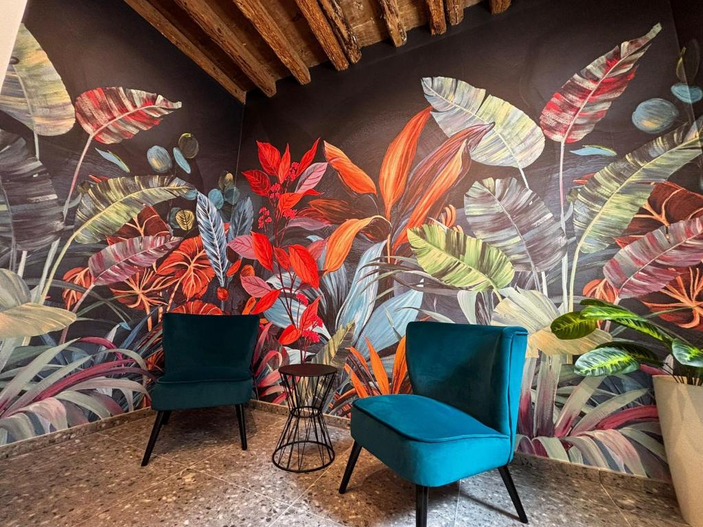 two chairs in front of a wall with a mural at Dimora Muneghette 181 ApartSuite House Chioggia in Chioggia