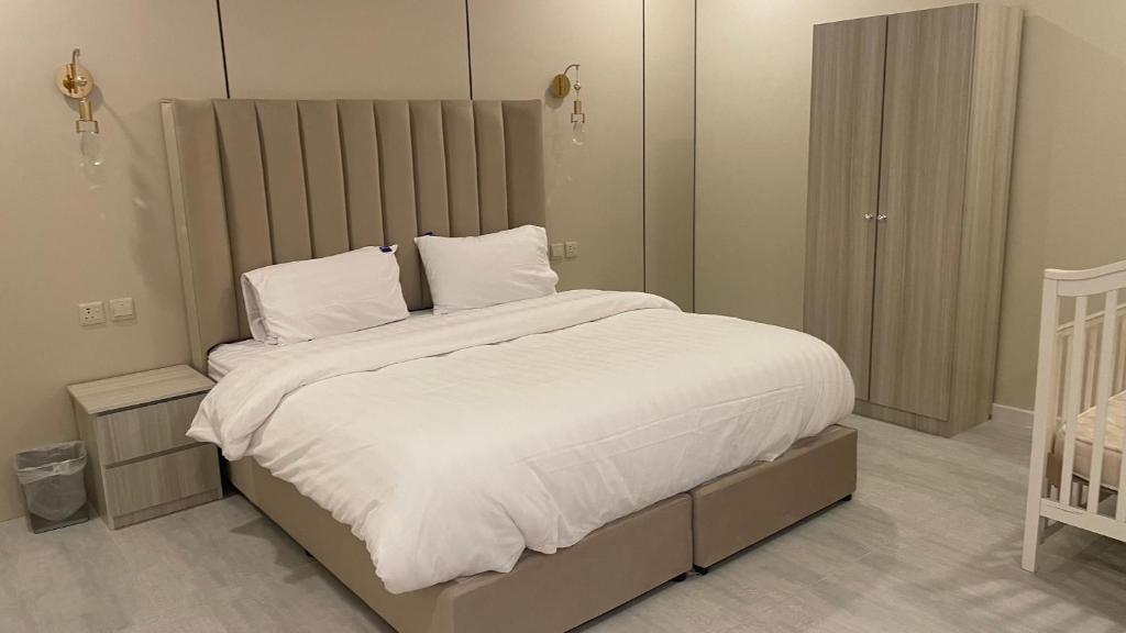 una camera da letto con un letto grande con lenzuola e cuscini bianchi di Taim a Yanbu