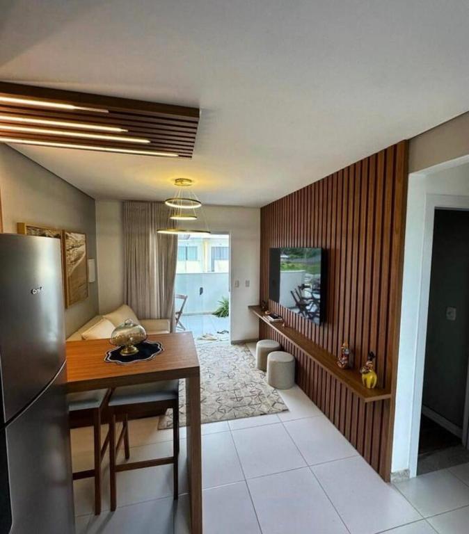 a kitchen and living room with a table and a refrigerator at High Standard coral beach in Santa Cruz Cabrália