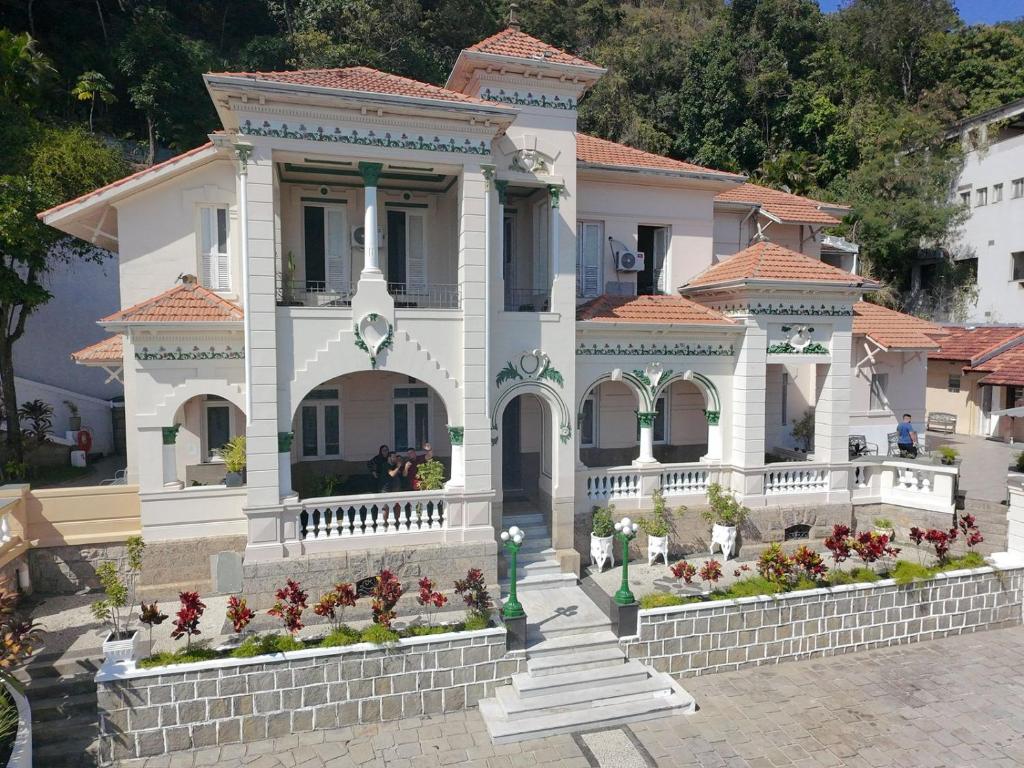 a large white house with flowers in front of it at Casa das Luzes Hostel IVN in Rio de Janeiro