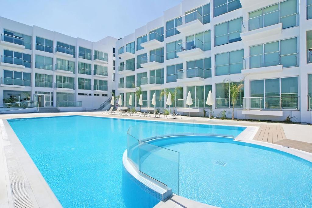 una gran piscina frente a un edificio en Too Coool Studio Apartment Coralli Resort, en Protaras