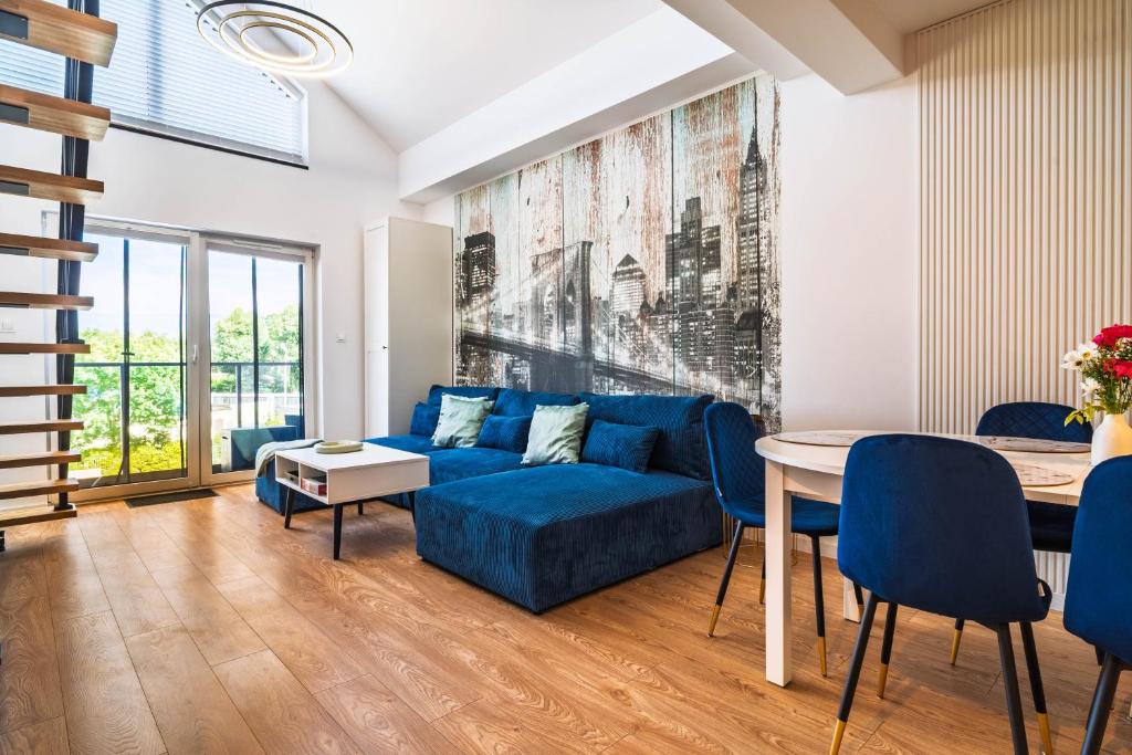 a living room with a blue couch and a table at Morze Apartamentów Apartament West Łeba A20 in Łeba