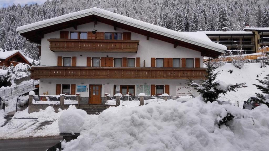 a house covered in snow with a pile of snow at Residenza Caola Sant'Antonio Mavignola in Madonna di Campiglio