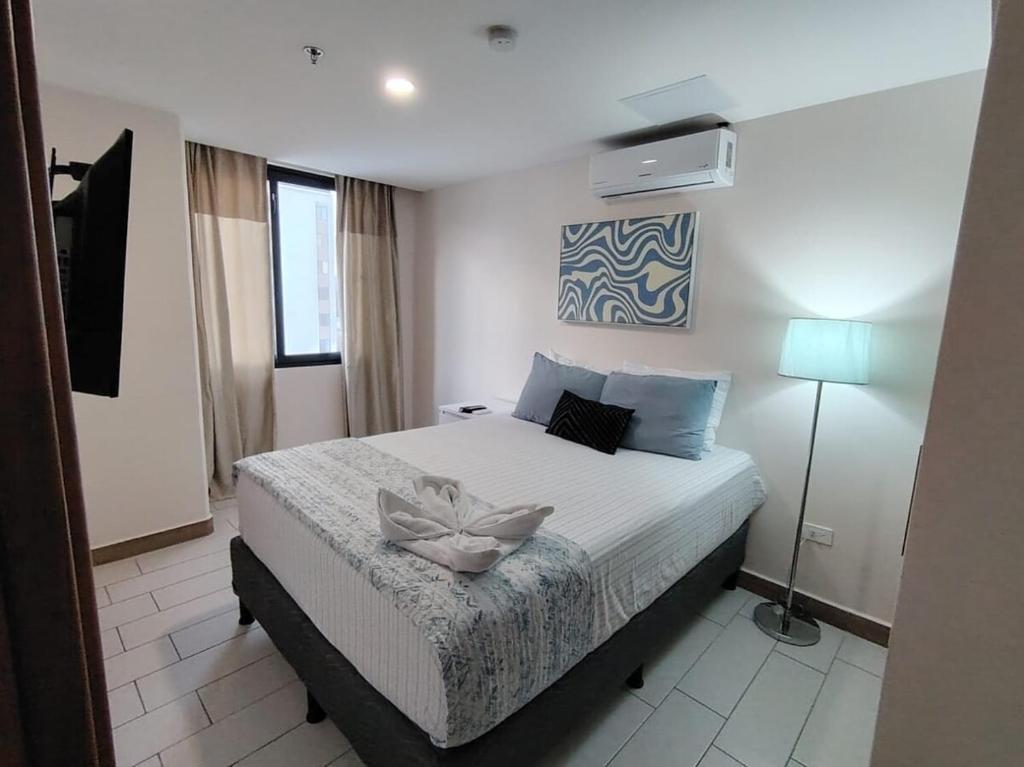 a bedroom with a large white bed with a lamp at Funcional, céntrico, El Oasis Urbano in Tegucigalpa