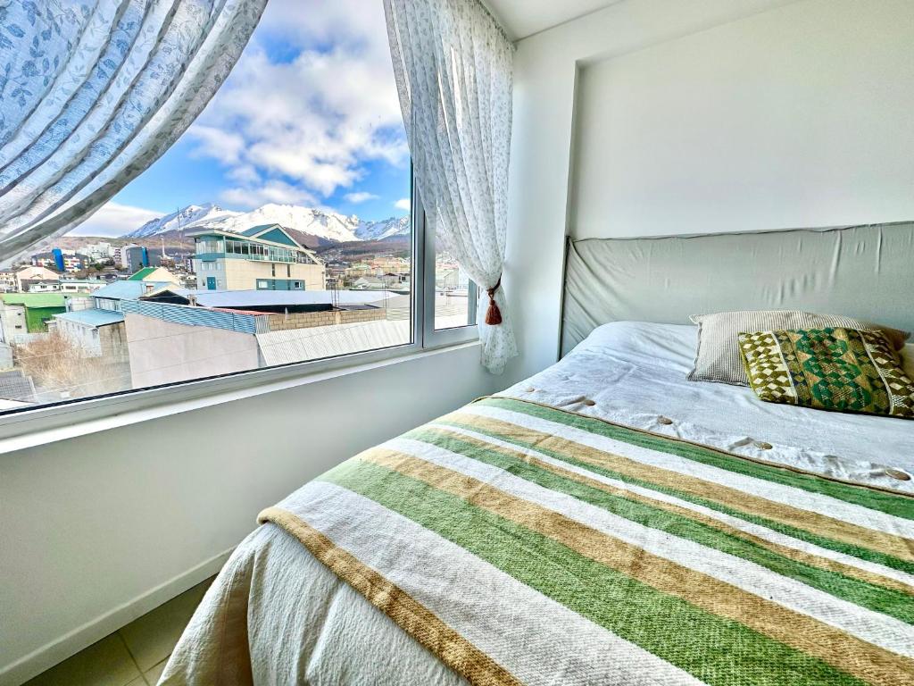 a bedroom with a bed and a window with a view at Austral Apartamentos in Ushuaia