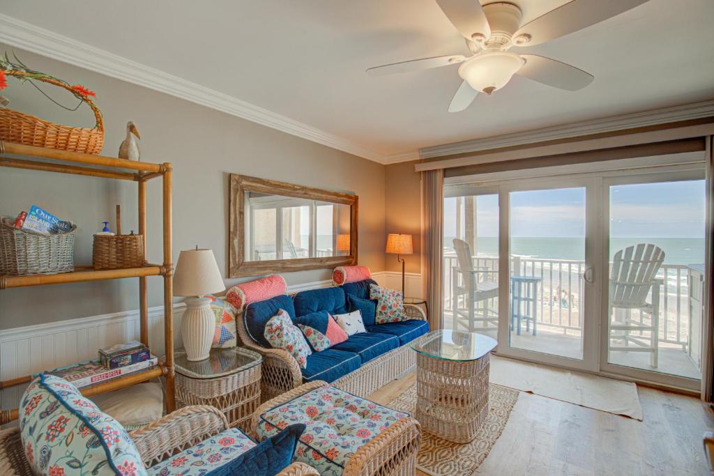 a living room with a blue couch and a balcony at Topsail Dunes 1107 in North Topsail Beach