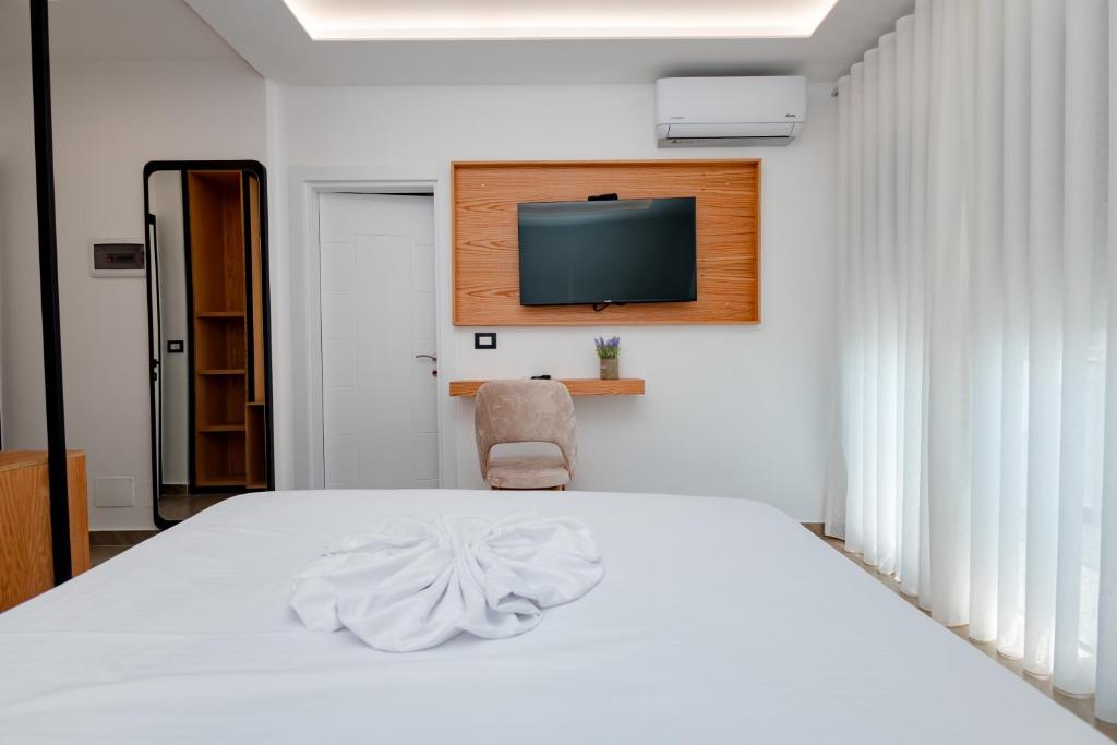 a bedroom with a white bed and a television at Paloka Collection Hotel in Shëngjin