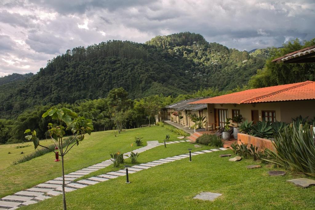 a garden with a house and mountains in the background at Hotel Mandalay 1941 in Pereira