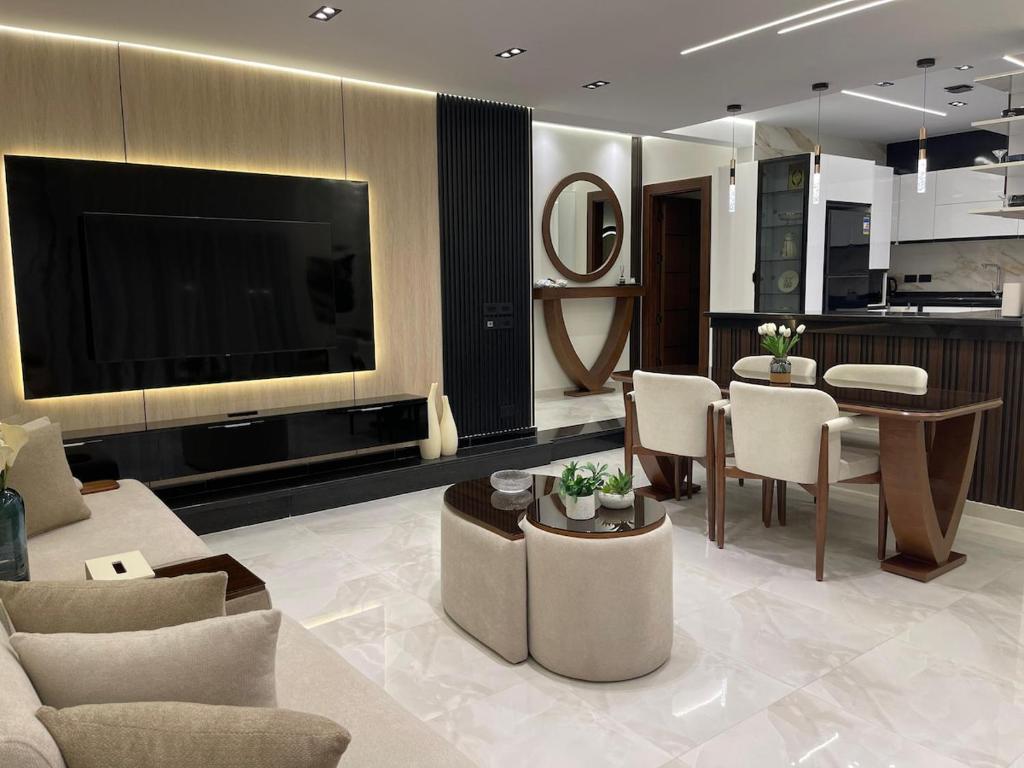 a living room with a television and a table and chairs at Brand New Apartment Obour City in Obour