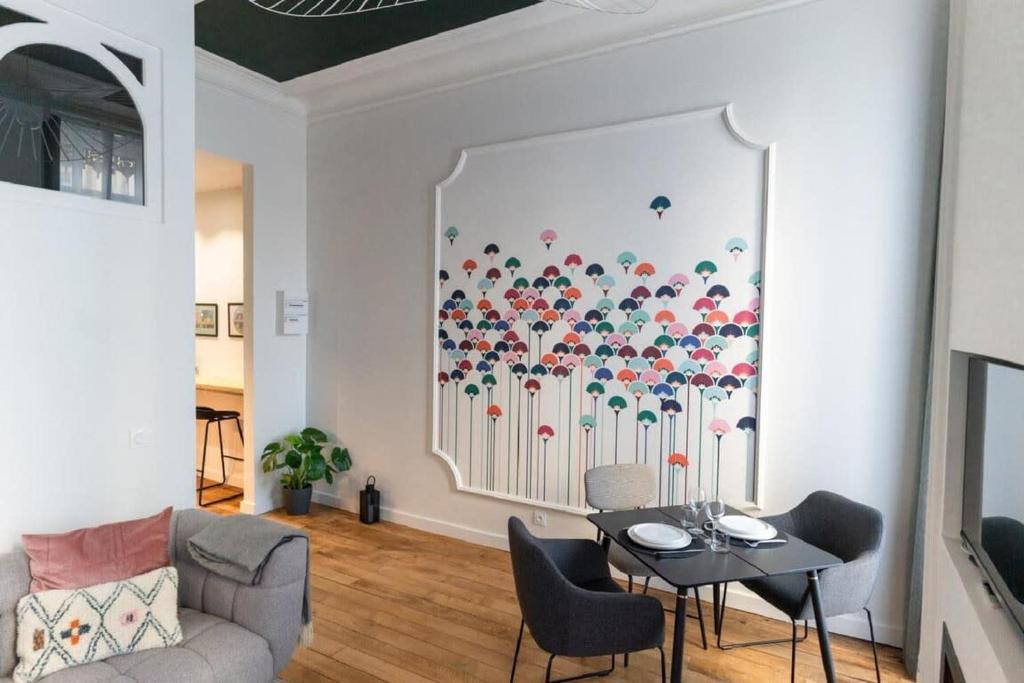 a living room with a table and a painting on the wall at Beige Hospitalité - Emma - hypercentre - appart' unique-parking in Saint-Étienne