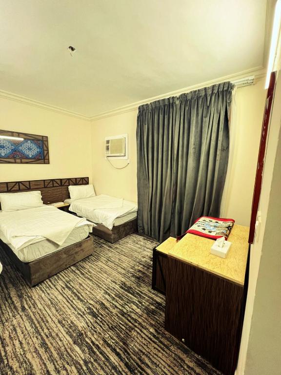 a hotel room with two beds and a window at دار الزائر1 in Al Madinah