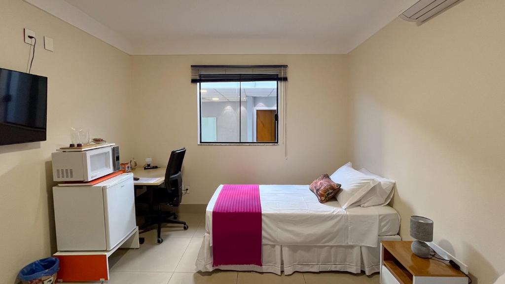 a bedroom with a bed and a desk with a computer at Apart Hotel Bena Taquaral in Campinas