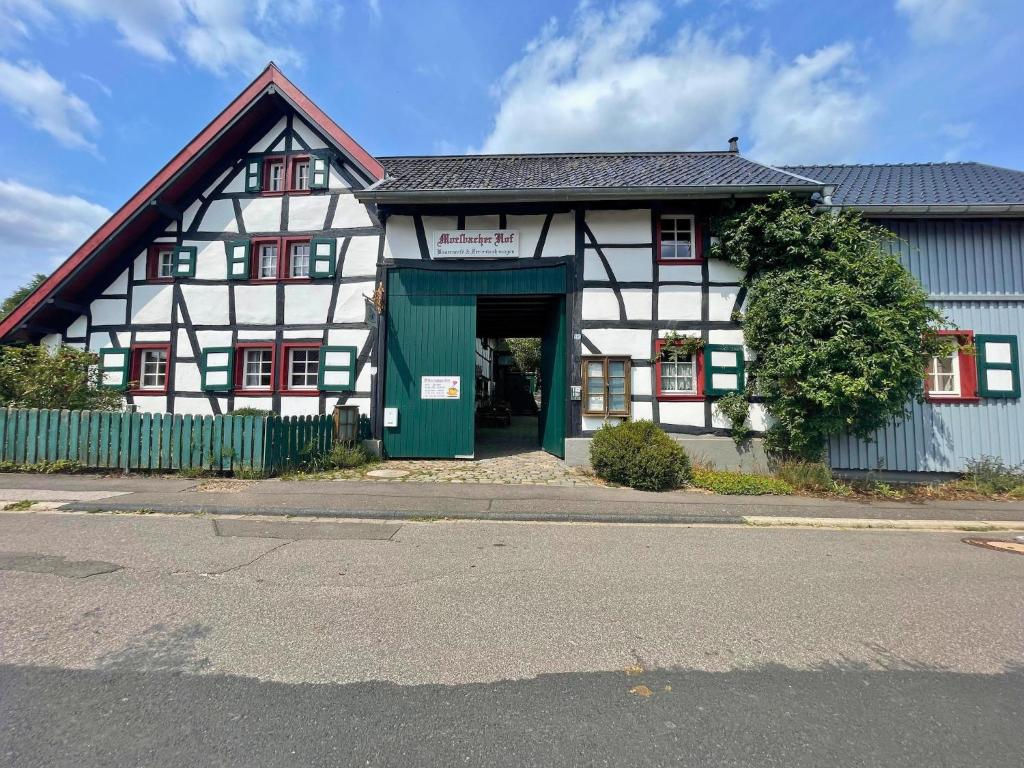 a white and black building with a green door at Ferienhaus Emma im Morsbacher Hof in Morsbach